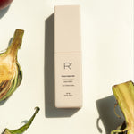 R/CUBED Foot care Hydro-Mist bottle on a light background surrounded by fresh artichokes and tomatoes, promoting clean foot care, soft feet, and skin nourishment with plant-based ingredients